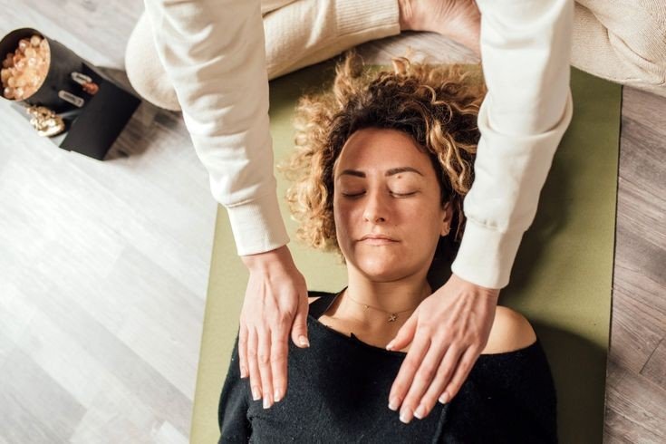 Hands offering supportive touch to shoulders during a Yin Yoga Meets Bodywork session